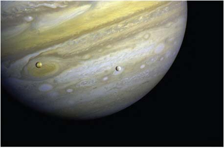 FIGURE 7.4 Jupiter, Io, and Europa. Jupiter’s Great Red Spot is a storm system nearly three times the diameter of Earth. There are orange deposits on volcanically active Io and a white icy crust on Europa. SOURCE: Courtesy of NASA/JPL.