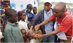 Two health workers give a child polio vaccine during a vaccination campaign in the Democratic Republic of the Congo.